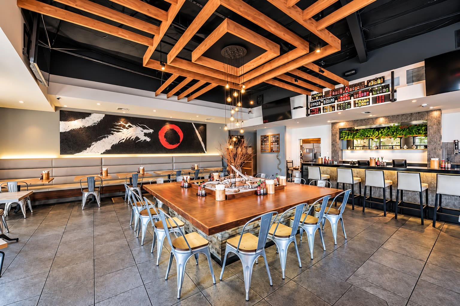 The Convoy dining room. A long communal table with metal chairs sits under a coffered ceiling of crossed wooden beams, with a black and red brush mural along the banquette wall and the bar and its bottle shelves running down the other side.