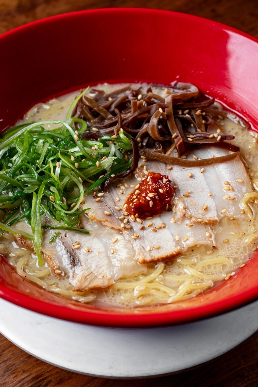 Traditional Tonkotsu Ramen, thin-sliced pork chashu, wood ear mushrooms, green onions and sesame seeds on pork bone broth